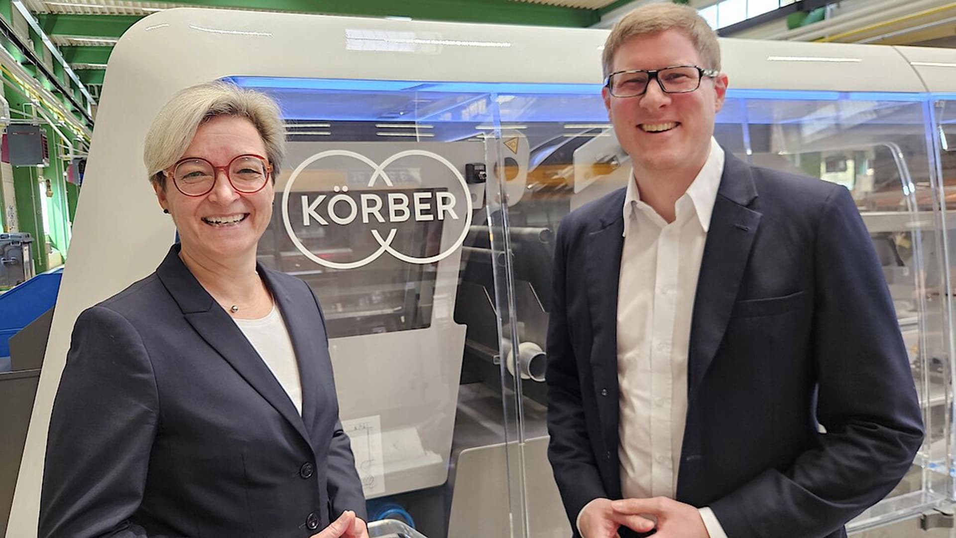 Volker Koch (rechts) und ein Mitarbeiter von Körber Pharma vor einer Verpackungsmaschine am Standort Schloss Holte-Stukenbrock.