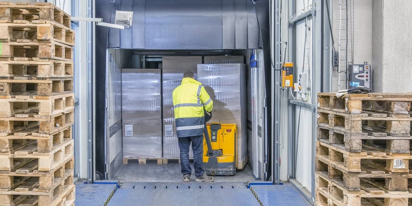 A worker is seen loading pallets into a container.