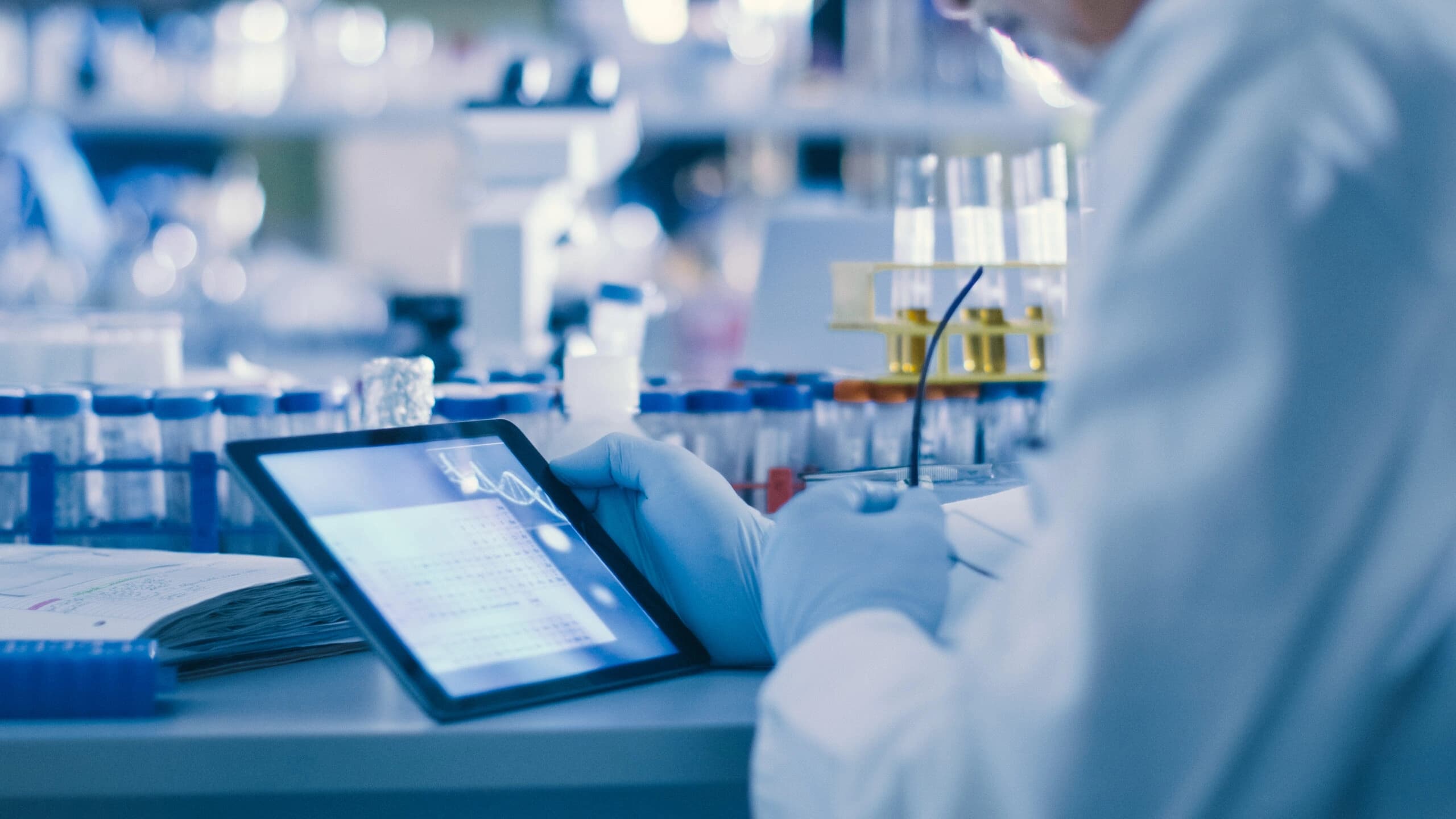 A man in a lab coat is focused on using a tablet in a laboratory setting