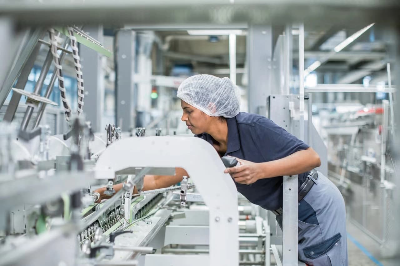 A woman focused on her tasks while working on a production line in a factory setting.