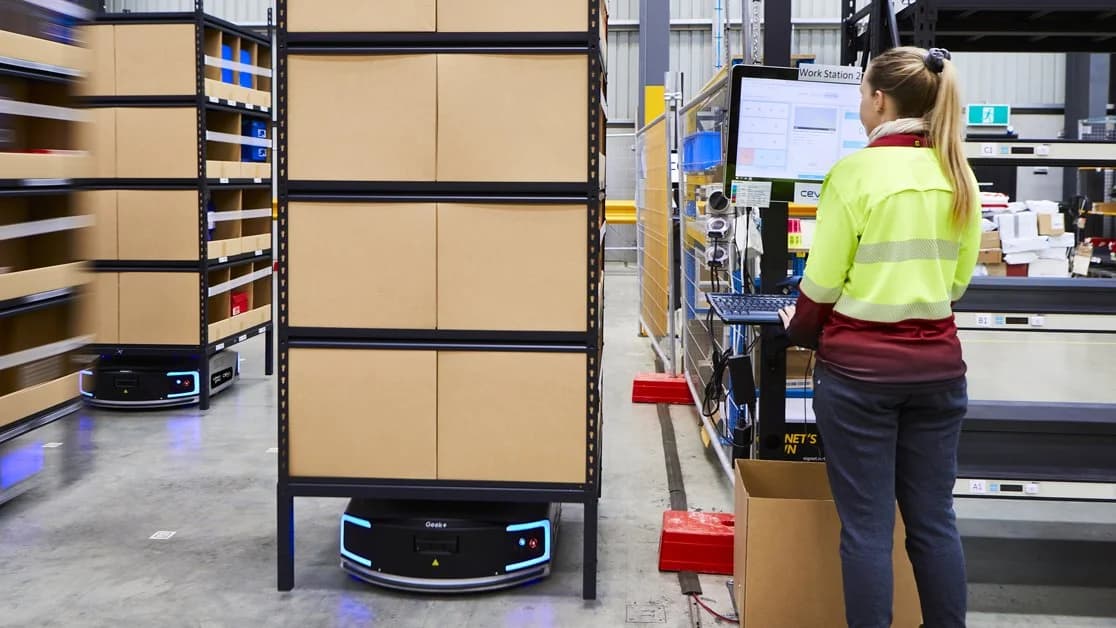 Eine Frau, die autonome mobile Roboter in einem Lager verwaltet.