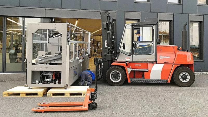 Gabelstapler transportiert eine Dividella NeoTop Verpackungsmaschine