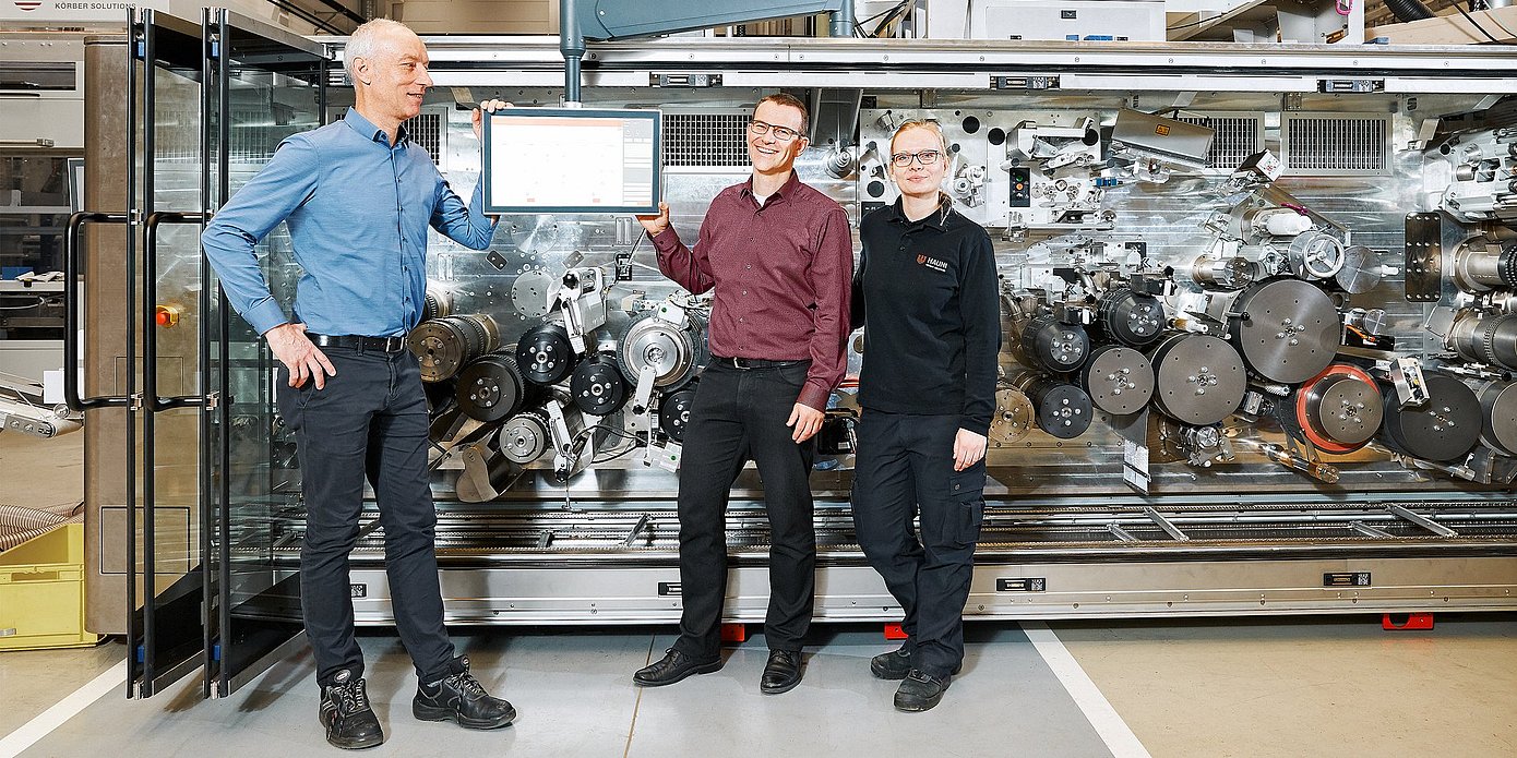 Photo of Hauni employees Karsten Barsch, Christian Junge and Nina Gröncke in front of a machine, the multi-segment maker