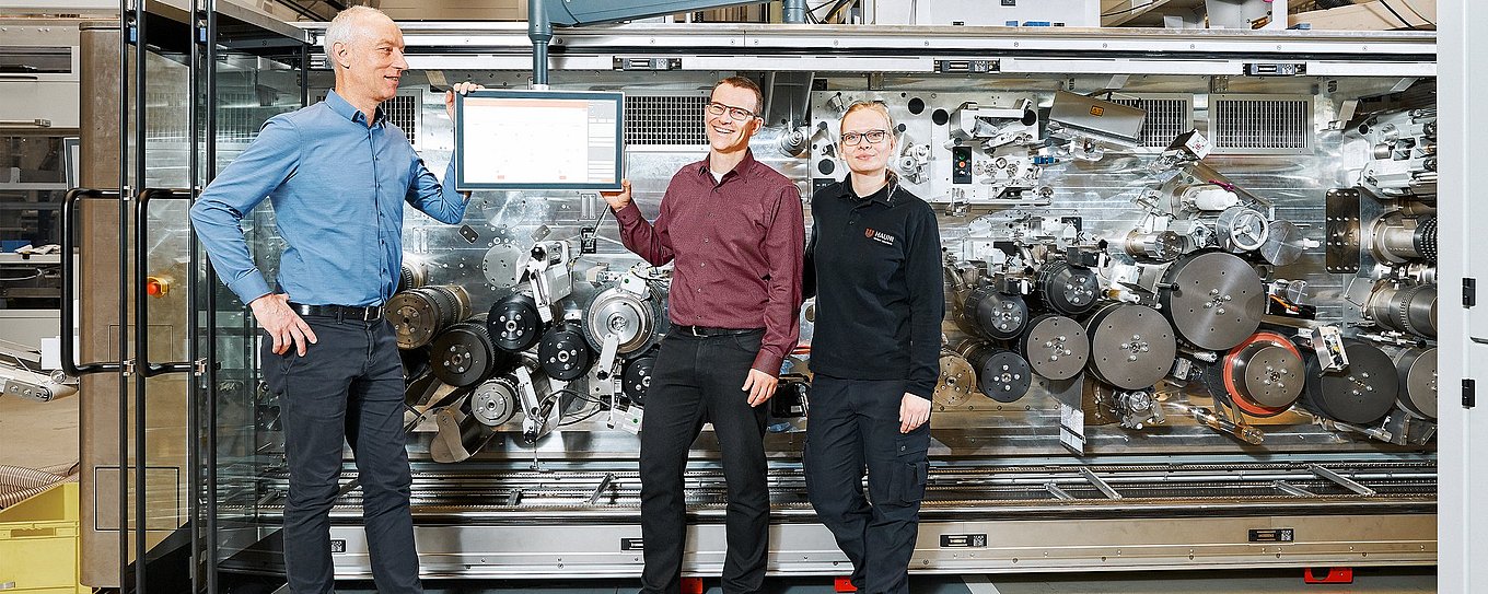 Foto der Hauni-Mitarbeiter Karsten Barsch, Christian Junge und Nina Gröncke vor einer Maschine, dem Multi-Segment-Maker