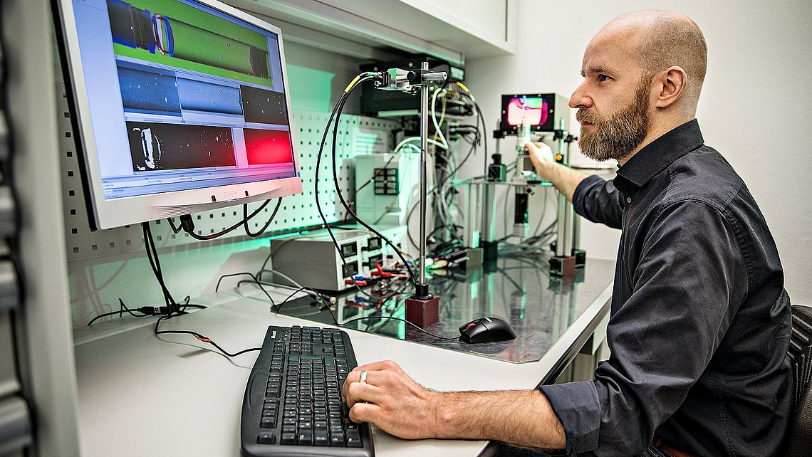 Photo of an engineer in a laboratory on a computer next to a set of measuring instruments