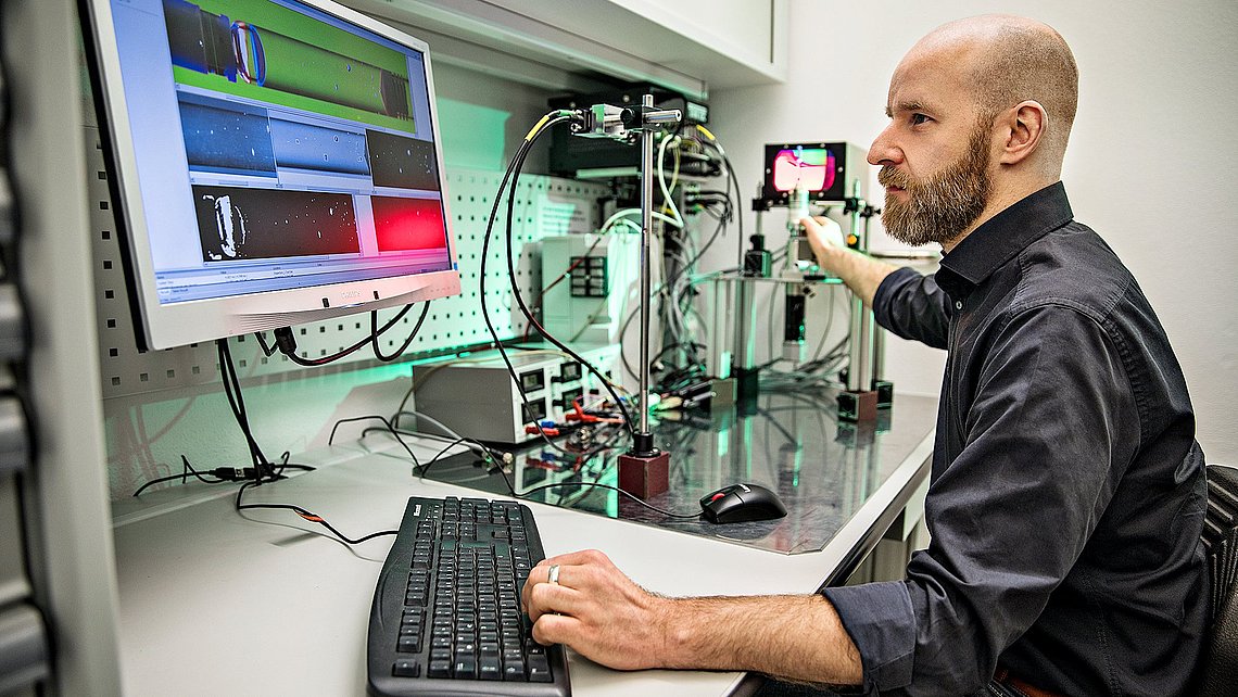 Photo of an engineer in a laboratory on a computer next to a set of measuring instruments