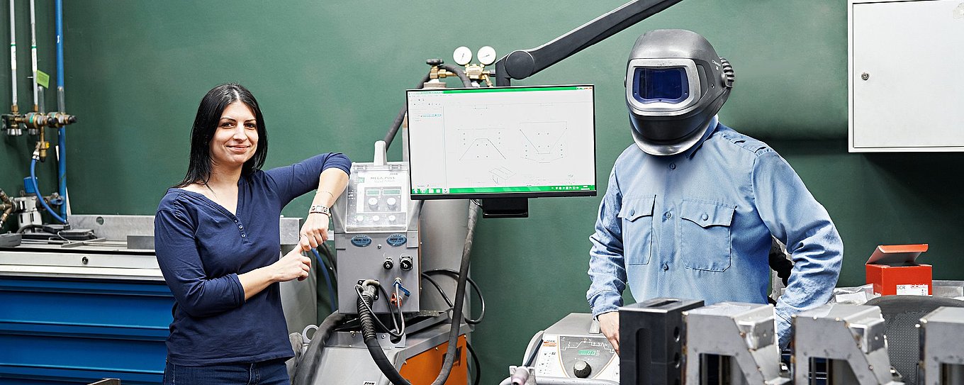 Employees Béata Szolnok and Ferenc Brozovac are standing at a welding workstation at Hauni Hungary