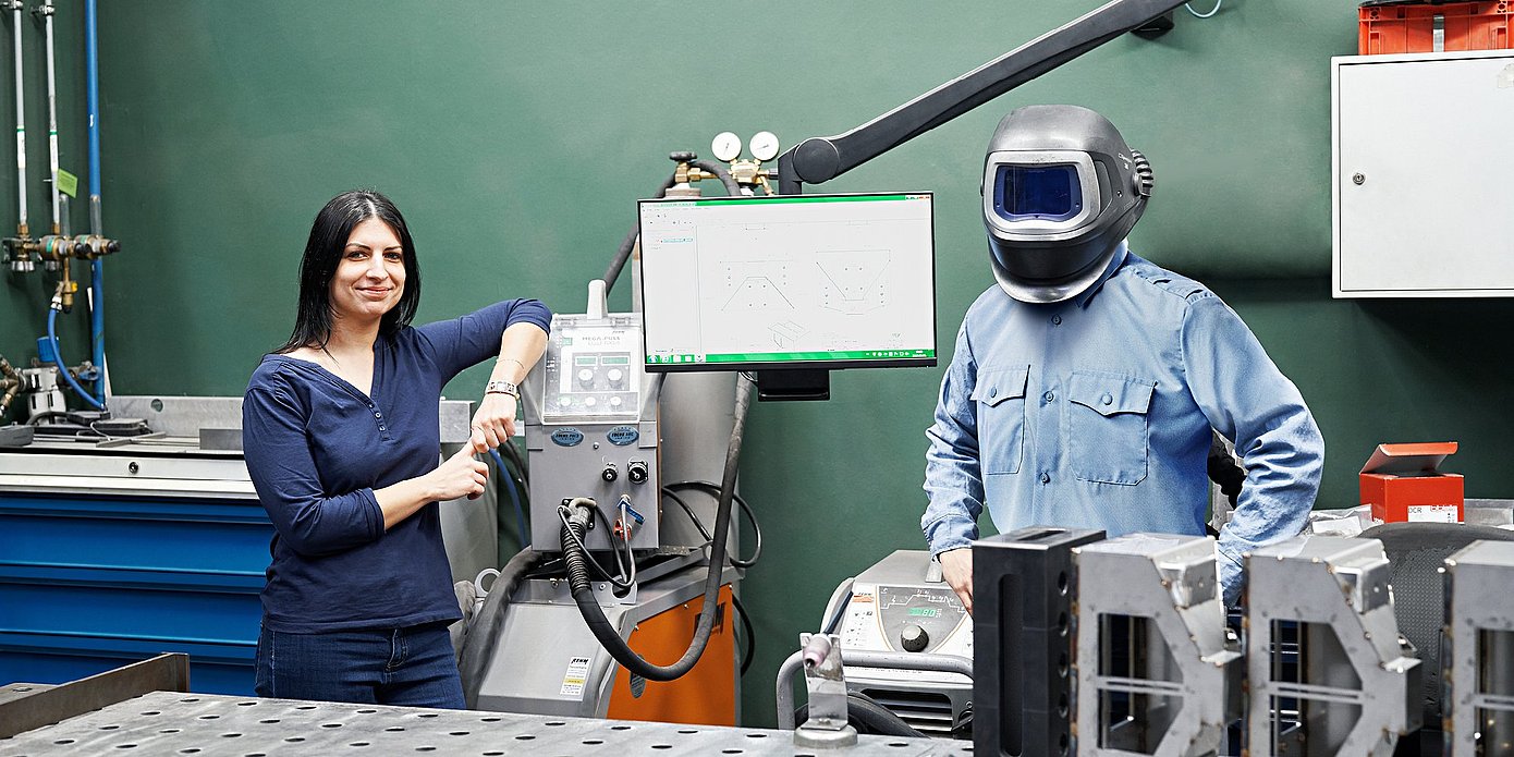 Employees Béata Szolnok and Ferenc Brozovac are standing at a welding workstation at Hauni Hungary