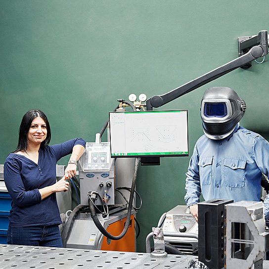 Employees Béata Szolnok and Ferenc Brozovac are standing at a welding workstation at Hauni Hungary