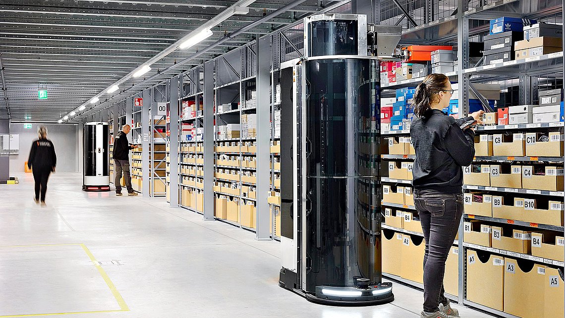 Photo of the Toru robot working next to humans in a high-bay warehouse. 